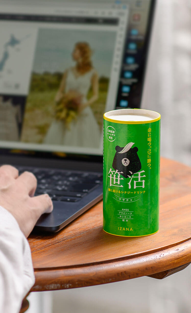 落ち着いた壁紙を背景に木目のテーブルがあり、お盆に乗ったガラスのコップに笹茶が注がれている様子が見える。透明感のある雰囲気が感じられる。